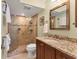 Bathroom with tiled walk-in shower, granite countertop and framed mirror, with neutral tones at 210 Santa Maria St # 244, Venice, FL 34285