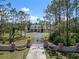 Lovely home exterior with a circular driveway and gated entrance, surrounded by mature trees and blue skies at 21616 67Th E Ave, Bradenton, FL 34211