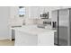 Close-up of a modern white kitchen featuring stainless steel appliances and quartz countertops at 2163 Blaser St, Port Charlotte, FL 33980