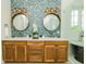 Dual vanities and tub create an elegant bathroom with mosaic tile backsplash and natural wood cabinetry at 221 Grant Dr, Sarasota, FL 34236
