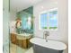 Bathroom featuring soaking tub, wood vanity, decorative wallpaper, and a window with a water view at 221 Grant Dr, Sarasota, FL 34236