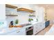 Bright kitchen with white cabinets, stainless steel appliances, and wooden floating shelves at 221 Grant Dr, Sarasota, FL 34236
