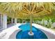 Relaxing poolside view featuring a thatched tiki umbrella and swaying palm trees at 221 Grant Dr, Sarasota, FL 34236