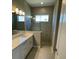 Contemporary bathroom with a frameless glass shower, neutral tiling, and a double vanity at 24835 Buckingham Way, Port Charlotte, FL 33980