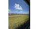 Expansive green space is viewed from a window under a bright sky at 24835 Buckingham Way, Port Charlotte, FL 33980