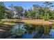 Scenic pond with lily pads reflecting the surrounding trees and a glimpse of the home in the background at 25305 83Rd E Ave, Myakka City, FL 34251