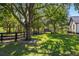 Landscaped yard featuring a black fence, large trees, and healthy green grass at 25305 83Rd E Ave, Myakka City, FL 34251