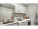 Laundry room with white cabinets, utility sink, modern washer and dryer, and quartz countertop for folding at 2932 Upper Tangelo Dr, Sarasota, FL 34239