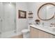 Stylish bathroom featuring a glass shower, modern vanity, and elegant round mirror at 301 Quay Commons # 503, Sarasota, FL 34236