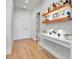 Modern hallway featuring a bar area with floating shelves, hardwood floors, and white walls at 301 Quay Commons # 503, Sarasota, FL 34236