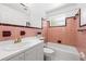 Retro bathroom featuring pink tile, a tub, and a sink with storage at 3427 Cambridge Dr, Sarasota, FL 34232