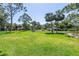 Expansive green lawn surrounded by mature trees and palm trees with a glimpse of a pool in the distance at 3500 El Conquistador Pkwy # 117, Bradenton, FL 34210
