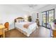 Cozy bedroom with a queen bed, wicker headboard, and sliding glass doors leading to a balcony at 3500 El Conquistador Pkwy # 117, Bradenton, FL 34210