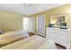 Charming bedroom with twin beds, white dresser and a bright yellow wall with view of closets at 3500 El Conquistador Pkwy # 117, Bradenton, FL 34210