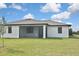 The home's rear exterior showcases a screened-in porch for seamless indoor-outdoor living and a lush, green lawn at 3836 Wenona Dr, North Port, FL 34288