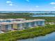 Aerial view of waterfront condo buildings with lush vegetation and lake backdrop at 388 Aruba Cir # 103, Bradenton, FL 34209
