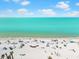 A vibrant beach scene with sunbathers, umbrellas, and clear turquoise waters under a sunny sky at 388 Aruba Cir # 103, Bradenton, FL 34209