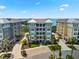 Exterior of condos with a blue/gray theme, tile roofs, tropical palms, and paver driveway at 388 Aruba Cir # 103, Bradenton, FL 34209