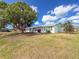 Exterior view of a charming home, featuring a lush lawn, a large tree, and mature landscaping at 3909 40Th W St, Bradenton, FL 34205