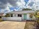 Charming home with a light-colored facade, turquoise door and shutters, complimented by tropical landscaping and a sunny sky at 3909 40Th W St, Bradenton, FL 34205