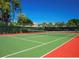 Outdoor tennis court with green and red surface, surrounded by lush greenery at 4640 Tower Hill Ln # 2325, Sarasota, FL 34238