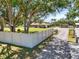 A single-story home with large trees and a long driveway behind a white fence at 5024 37Th E St, Bradenton, FL 34203