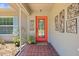 A front porch with a red tile floor, a red front door, and wrought iron wall decor at 5024 37Th E St, Bradenton, FL 34203
