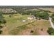 Sprawling acreage featuring multiple buildings, including the main residence, surrounded by lush green pastures and scattered trees at 5235 Spencer Parrish Rd, Parrish, FL 34219