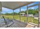 Relaxing screened porch with seating, offering a view of the spacious yard and outbuildings at 5235 Spencer Parrish Rd, Parrish, FL 34219