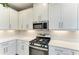 Modern kitchen features white cabinets, stainless steel microwave and gas range at 5583 Summit Gln, Bradenton, FL 34203