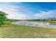Scenic lake view with lush green grass, clear water reflecting the sky, and residential homes in the distance at 5583 Summit Gln, Bradenton, FL 34203