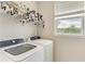 Bright laundry room featuring a window with blinds, a washer, and a dryer with hanging rod at 5583 Summit Gln, Bradenton, FL 34203