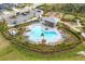 Aerial view of a community pool surrounded by lush landscaping, a playground, and ample parking at 5583 Summit Gln, Bradenton, FL 34203