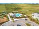 Aerial view of a community pool with a cabana, pool furniture, parking area, and green space at 5583 Summit Gln, Bradenton, FL 34203