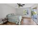 Bedroom featuring a ceiling fan, wood floors, a window, and sliding glass doors to the backyard at 5711 Garden Lakes Fern, Bradenton, FL 34203