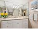 Bright bathroom with a large mirror, white cabinets and a view to the living area and outside at 6204 Midnight Pass Rd # 102, Sarasota, FL 34242