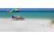Relaxing beach scene with beach chairs and umbrella set against a backdrop of clear blue waters at 6204 Midnight Pass Rd # 102, Sarasota, FL 34242