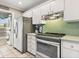 Modern kitchen featuring stainless steel appliances and adjacent laundry area at 6204 Midnight Pass Rd # 102, Sarasota, FL 34242