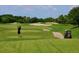 Scenic view of a golfer teeing off on a lush green golf course with sand traps and a golf cart nearby at 6642 Willowshire Way, Bradenton, FL 34212