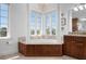 Bright bathroom features a soaking tub surrounded by large windows and wood cabinets at 6802 68Th E Ave, Bradenton, FL 34203