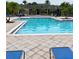 Large pool with shallow end, surrounded by palm trees and blue lounge chairs at 7411 Vista Way # 102, Bradenton, FL 34202