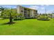 Beautiful condo exterior with well-manicured green lawn and tropical landscaping at 845 Benjamin Franklin Dr # 101, Sarasota, FL 34236