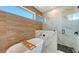 Stylish bathroom featuring a soaking tub, wood accent wall, and a glass-enclosed shower with marble tile at 8800 Midnight Pass Rd, Sarasota, FL 34242