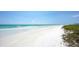 Expansive white sandy beach with gentle waves, clear skies, and a serene atmosphere at 8800 Midnight Pass Rd, Sarasota, FL 34242
