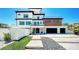 Contemporary three-story home with a sleek exterior, spacious garage, and minimalist landscaping at 8800 Midnight Pass Rd, Sarasota, FL 34242