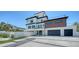 Three-story home with a sleek exterior, spacious garage, modern landscaping, and charming front porch at 8800 Midnight Pass Rd, Sarasota, FL 34242