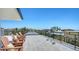 Wide angle view of the rooftop deck with patio furniture and metal railing showcasing beautiful treetop and ocean views at 8800 Midnight Pass Rd, Sarasota, FL 34242