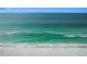 A lone person walks the beach in this aerial view of waves lapping on a white sandy shore at 89 Avenida Messina, Sarasota, FL 34242