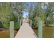 Picturesque view down the wooden dock surrounded by lush trees leading to chairs overlooking the water at 891 Palmetto Ne Dr, Port Charlotte, FL 33952