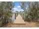 A wooden dock extends into the water, framed by trees and shrubs and the hint of houses across the canal at 891 Palmetto Ne Dr, Port Charlotte, FL 33952